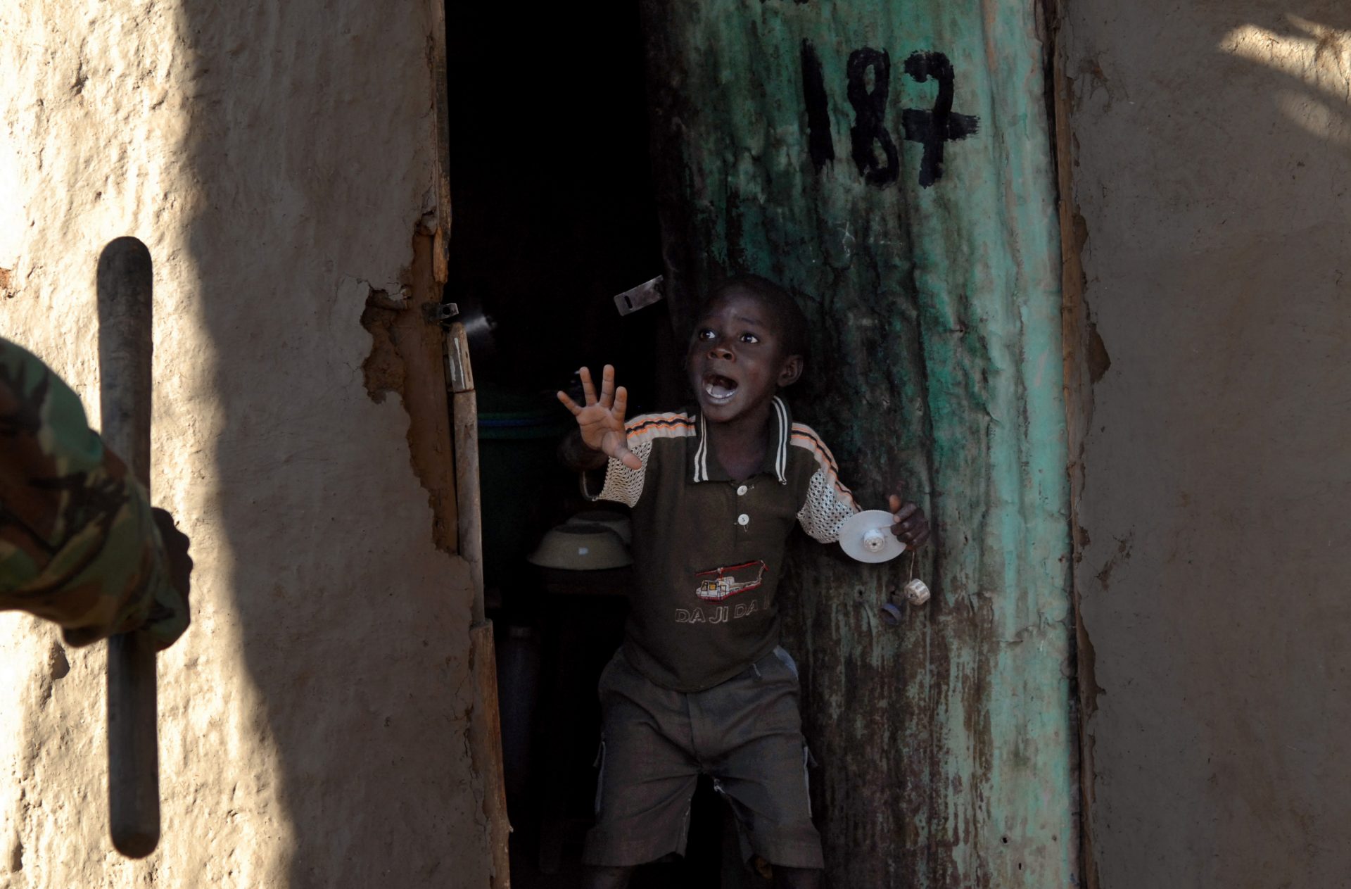 NAIROBI, KENYA, JANUARY 17, 2008:  Monday Lawiland, 7 years old, screams as he sees kenyan policeman with a baton approach the door of his home in the Kibera slum of Nairobi.(Photo by Walter Astrada)